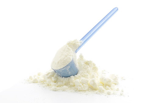 A pile of Baby Milk Formula with a measuring scoop, isolated on white.