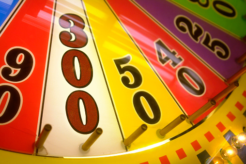 A close-up view of a wheel of fortune game focusing on the 300 points. This photo was taken at a seaside arcade hall and features a brightly colored wheel of chance ringed with flashing clear incandescent bulbs. The ocassional higher numbers, like 300, are placed next to much lower numbers (less than 100.) The lower numbers are displayed vertically in black, while the higher numbers, like 300 are displayed vertically in a color.