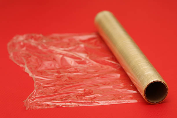 Cling film rolling on a red background Cling film on red background polythene photos stock pictures, royalty-free photos & images