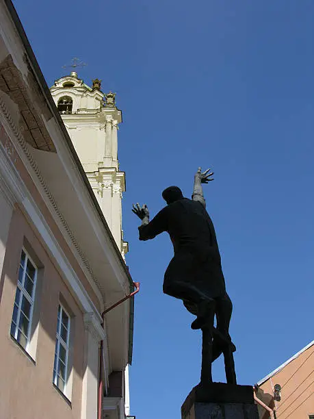 "Sculpture in a sidestreet of Vilnius, Lithuania, of a man reaching-out towards a church."