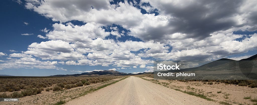 Desert Road, Cloudy Sky Unpaved road in a remote valley in central Nevada. Dirt Road Stock Photo