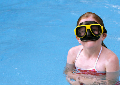 Young girl with goggles in a swimming pool.Tons of copy space.