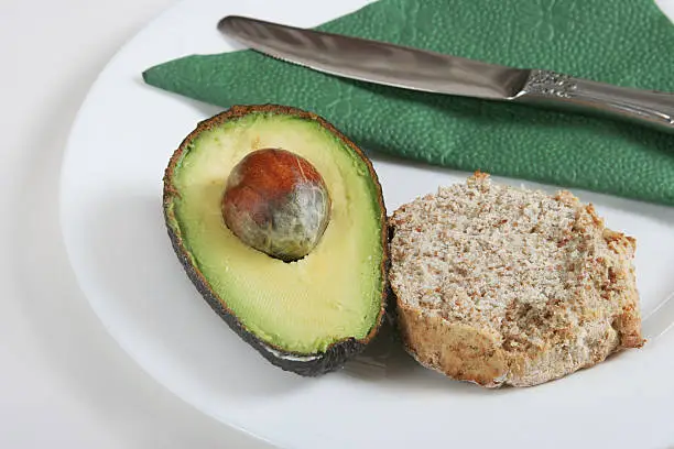avocado and brown bread isolated on white with plate,napkin and knife
