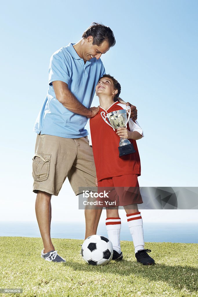 Happy father with his son holding a winners trophy Portrait of a happy mature father with his son holding a winners trophy - Outdoors Father Stock Photo