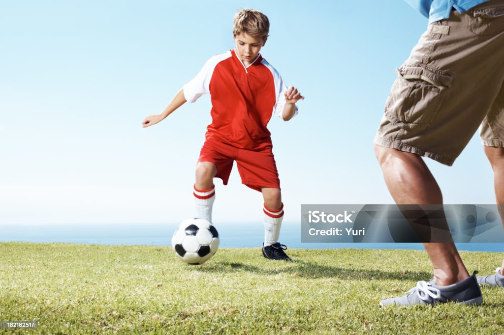 Petit garçon jouant un match de football avec son père - Photo de Compétition sportive scolaire libre de droits