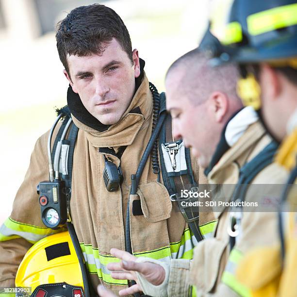 Bomberos Con Engranajes En Escuchar Colegas Hablando De Bombero Foto de stock y más banco de imágenes de Bombero