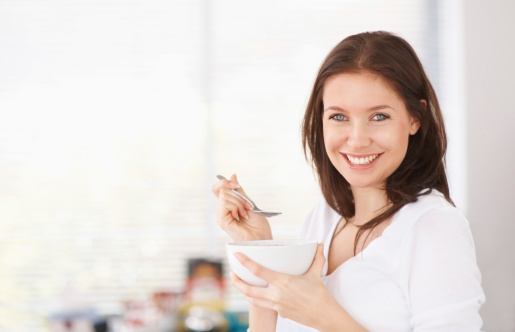 Healthy eating - Portrait of a happy woman having a bowl of cereals while at home