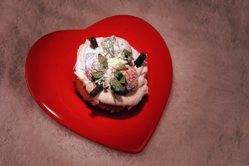 spotlight on a cupcake on heart shaped plate on a white sugary background