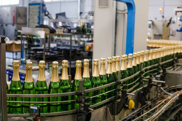 зеленые бутылки с шампанским вином движутся по конвейеру на заводе игристых вин. производство шампанского. - bottling plant brewery industry food стоковые фото и изображения