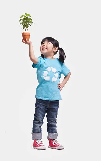 Photo of Studio shot little girl holding potted plant over her head