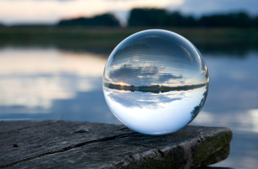 a crystal ball sits on a wooden footbridge over a pondsuche