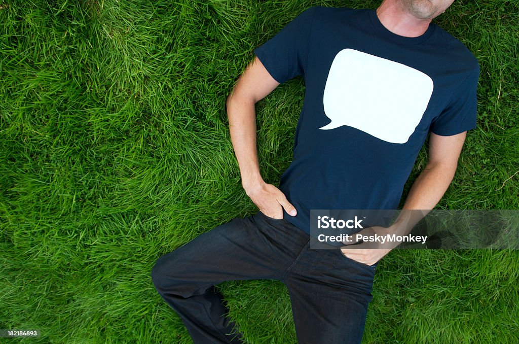 音声バブルの青色の T シャツの上に横になって、屋外の芝生男性 - Tシャツのロイヤリティフリーストックフォト