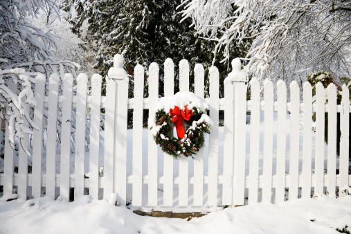 a christmas wreath on a white picket fence on a snowy day for more Christmas photos look in the lightbox below