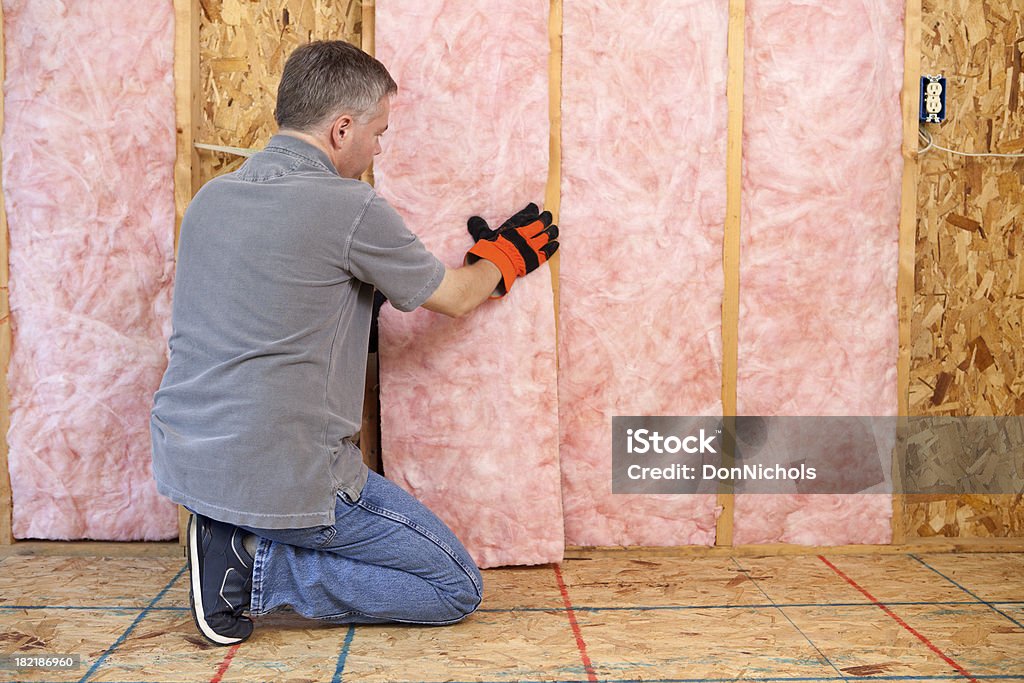 Man Installing Insulation Man installing fiberglass insulation in the wall.Please also see: Insulation Stock Photo