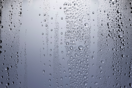Rain or water drops different size on a black shiny car hood surface. Water droplets on dark iron surface and texture. Abstract background and water texture for design
