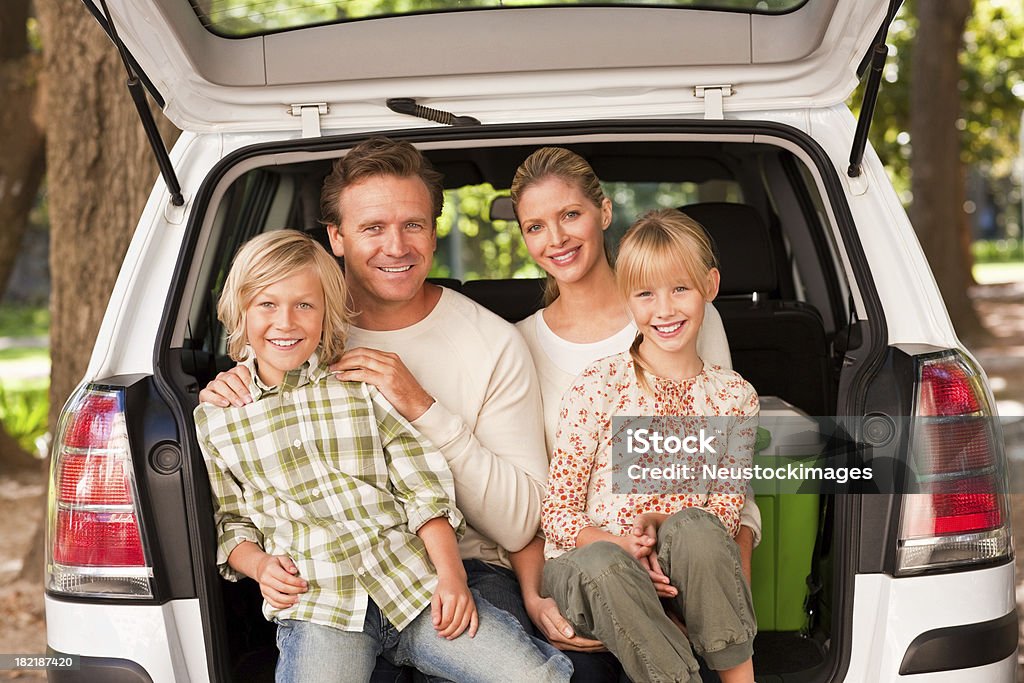 Famiglia seduto sul portellone posteriore di una monovolume - Foto stock royalty-free di 8-9 anni