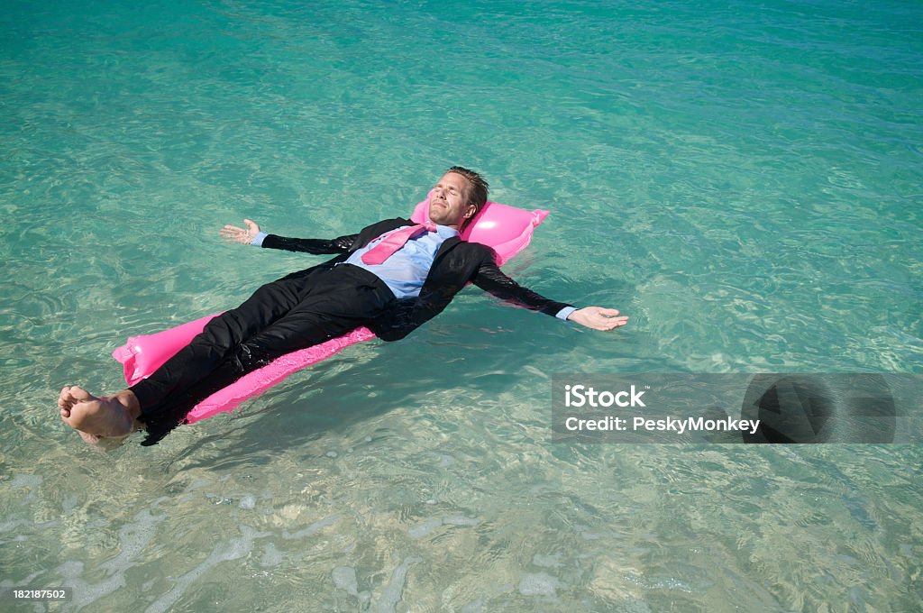 Homme d'affaires détente flotter sur Rose Matelas pneumatique - Photo de Homme d'affaires libre de droits