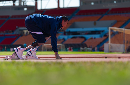 Runner using starting block to start his run on running track in a stadium. Athlete starting his sprint on an all-weather running track.