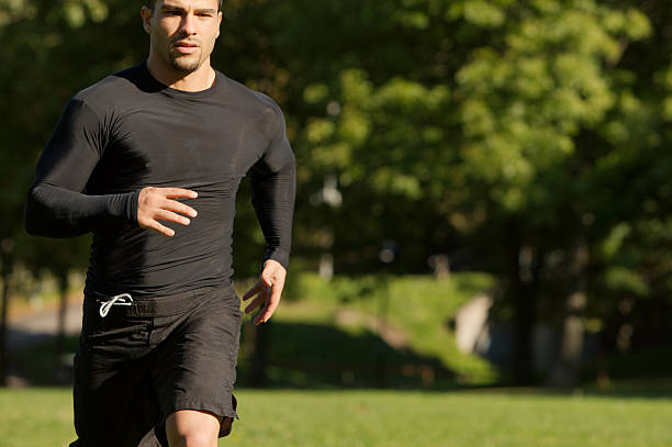 istock Athletic man running through the park 182187707
