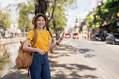 Asia woman tourist walking and using a smart phone in the street in a sunny summer