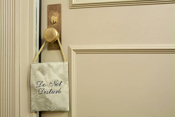 A fabric 'do not disturb' sign hanging on a cream door stock photo
