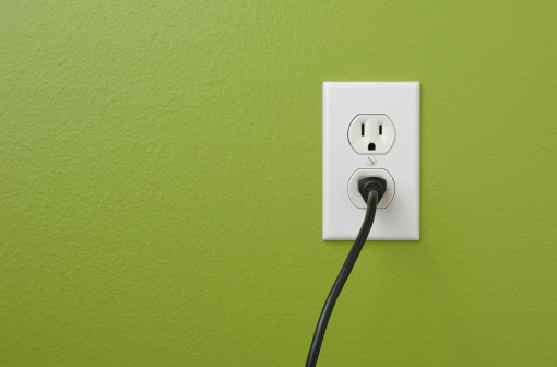 Electrical power outlet against a green painted wall.related: