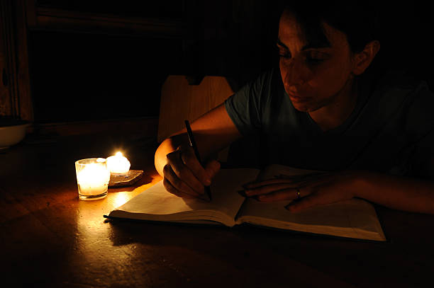 Woman Writing by Candlelight stock photo
