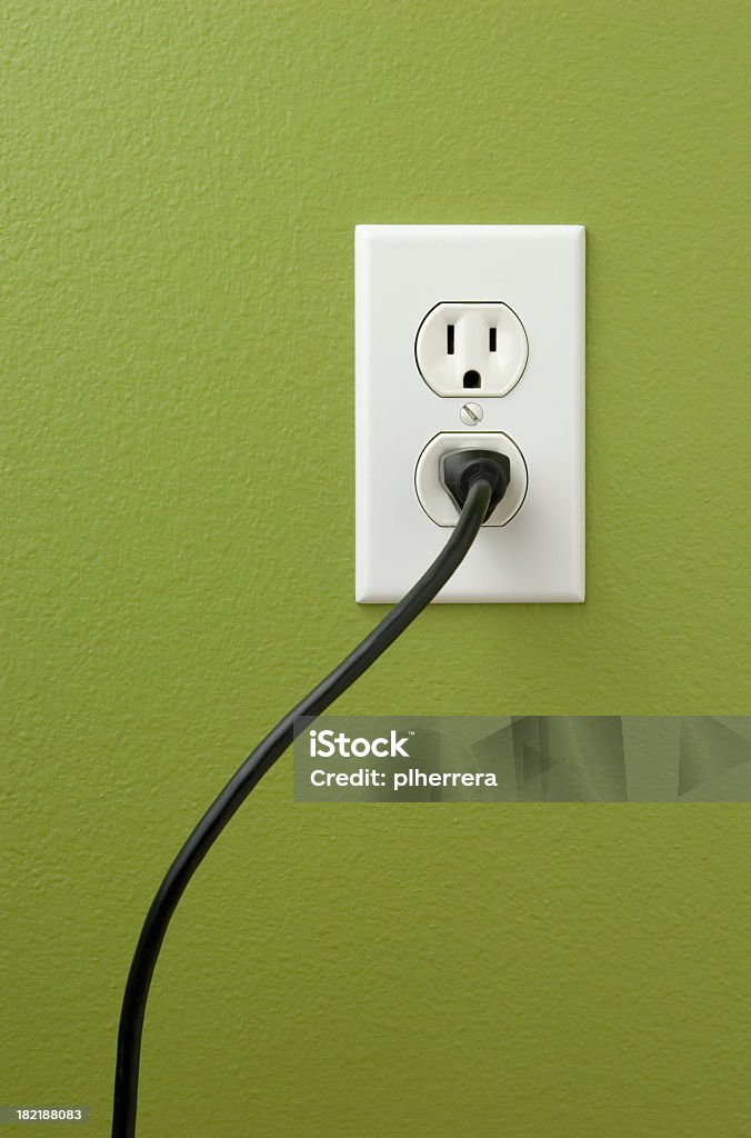 An electrical outlet with a plug inserted Electrical power outlet against a green painted wall.related: Electrical Outlet Stock Photo