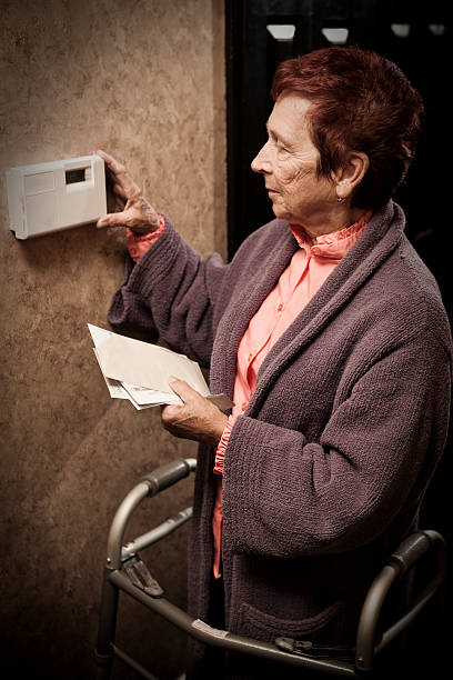 mulher idosa olhando para contas e termostato - unemployment fear depression women imagens e fotografias de stock