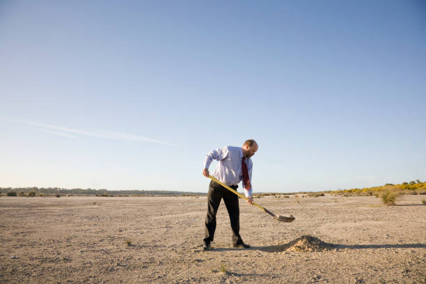 Digging Hole Well dressed man digging a hole. burying stock pictures, royalty-free photos & images