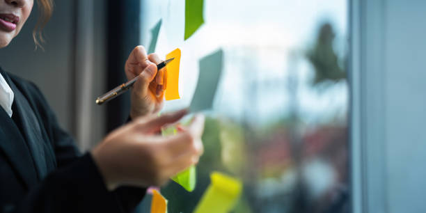 istock Young creative business woman Asian using sticker note in glass wall to writing strategy business plan to development growth to success 1821883030