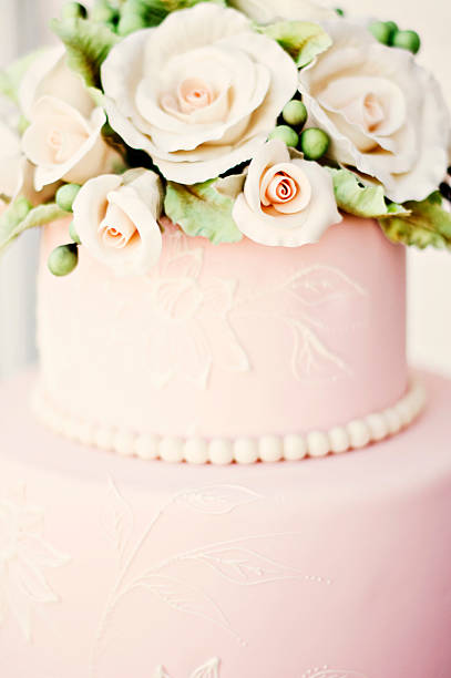 Pink Wedding Cake with Roses Beautiful pink fondant cake with beaded frosting and topped with roses. wedding cake close up macro stock pictures, royalty-free photos & images