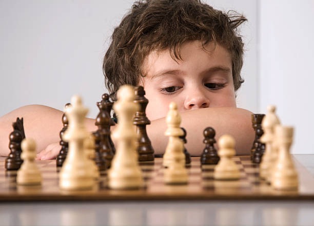 istock Small boy deep in thought as he contemplates his chess move 182188345