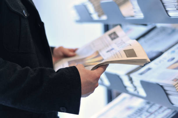 Reading the news Young business man holding a newspaper and reading the news. news stand stock pictures, royalty-free photos & images