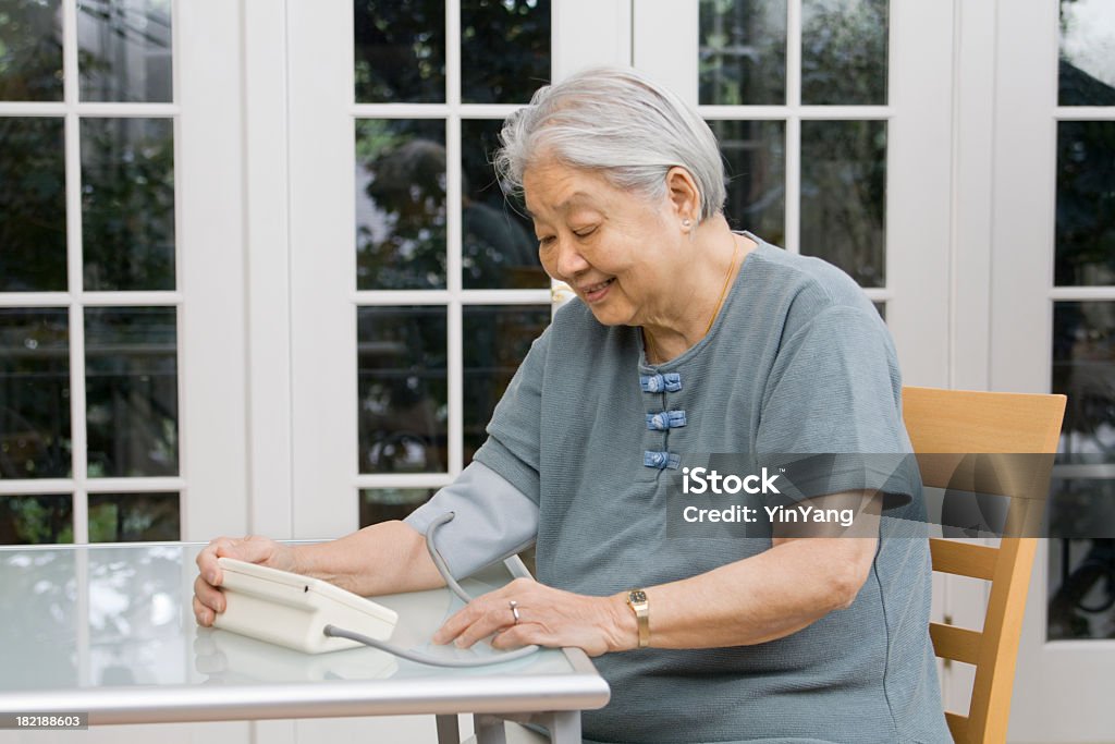 Старший азиатская женщина, мониторинга ее артериальное давление Гц - Стоковые фото Диабет роялти-фри