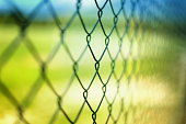 Close-up section of a chain-link fence with field behind it