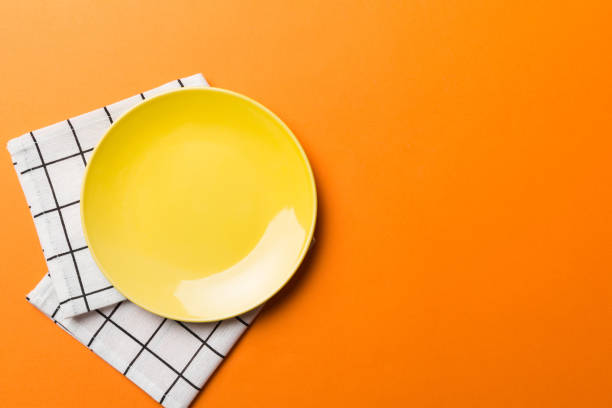 istock Top view on colored background empty round yellow plate on tablecloth for food. Empty dish on napkin with space for your design 1821888457