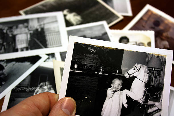 Hand holds Vintage photograph of child with hobby horse toy stock photo