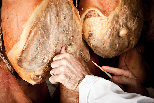 Elderly person handling Parma ham Parma ham (Prosciutto di Parma) quality testing. parma italy stock pictures, royalty-free photos & images