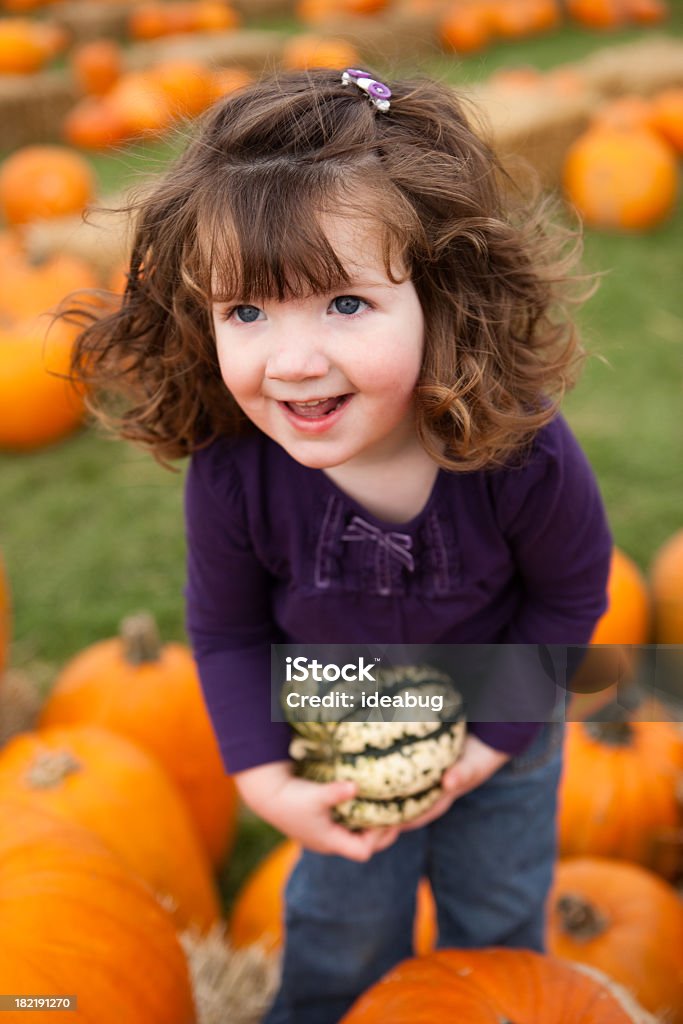 Fillette heureuse dans un champ de potirons tenant une gourde - Photo de 2-3 ans libre de droits