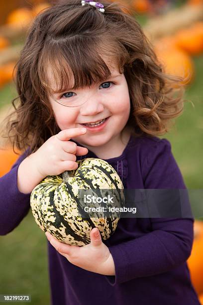 Szczęśliwa Dziewczynka W Pole Dyniowe Trzyma Dyniowate - zdjęcia stockowe i więcej obrazów Dynia