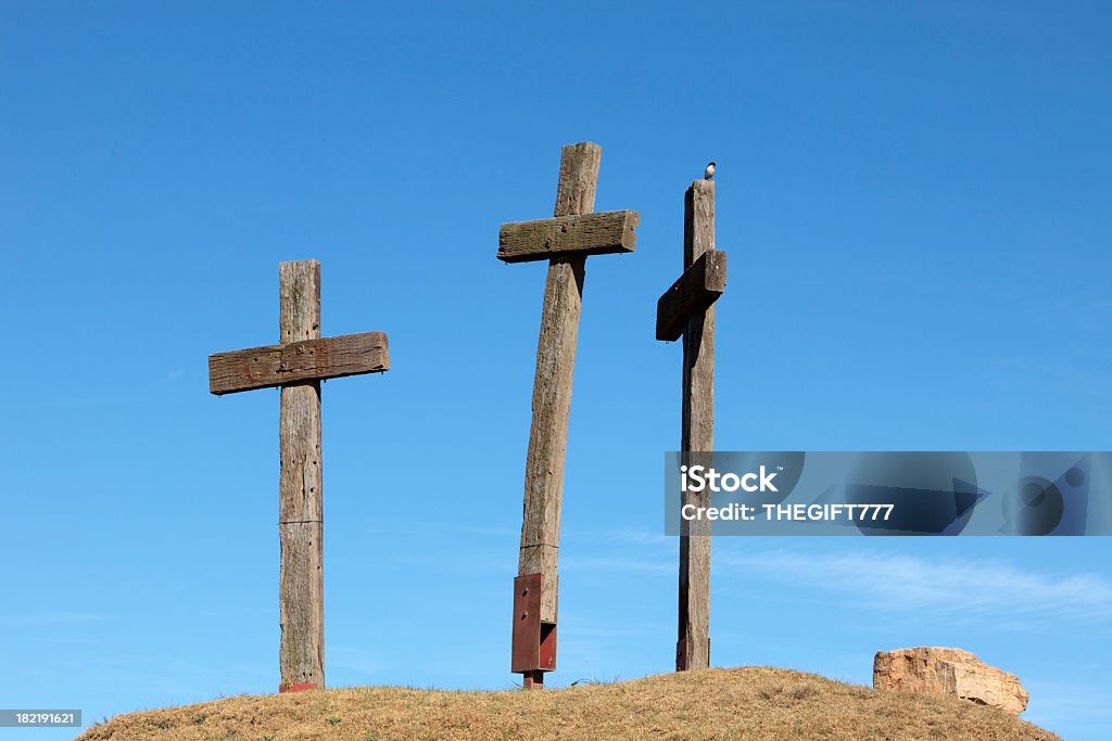 Three Crosses on a Hill Three wooden crosses seen on a hill, resembling christian faith, seen against a clear blue sky Amish Stock Photo