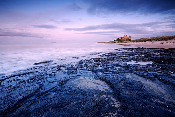 castillo de bamburgh al atardecer - bamburgh northumberland england beach cloud fotografías e imágenes de stock