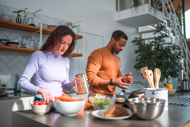 istock Mid Adult Multiracial Couple Using Digital Tablet While Making Breakfast At Home 1821950651