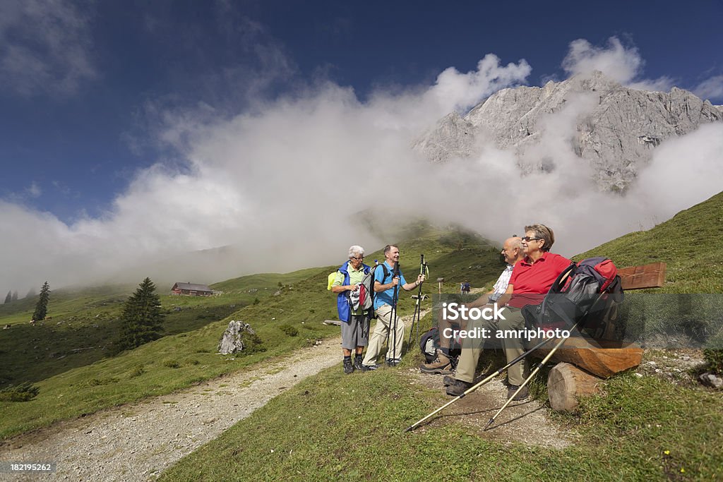 hikers senior en breve descanso en banco en hermosas montañas - Foto de stock de 60-69 años libre de derechos