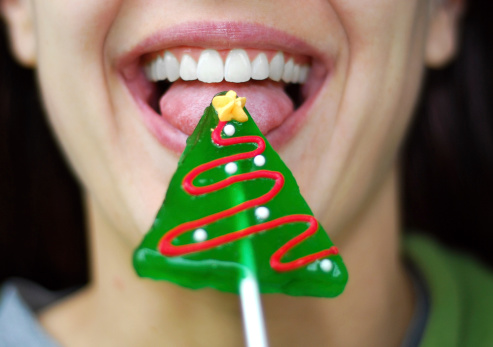 Close up of a woman with Christmas tree lollipop.See also