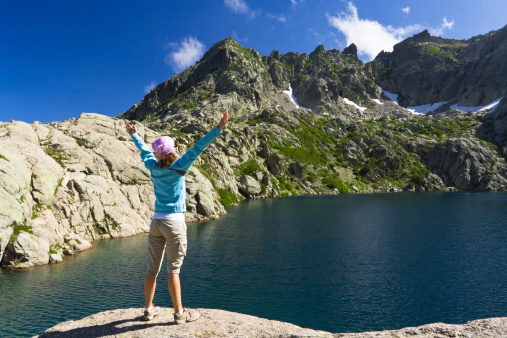 female hiker standing in front of a mountain lake expressing happinessCHECK OTHER SIMILAR IMAGES IN MY PORTFOLIO....
