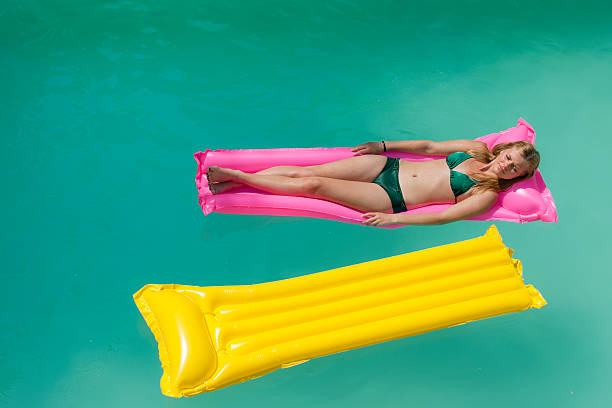 istock sunbathing girl on pink pool raft 182195793
