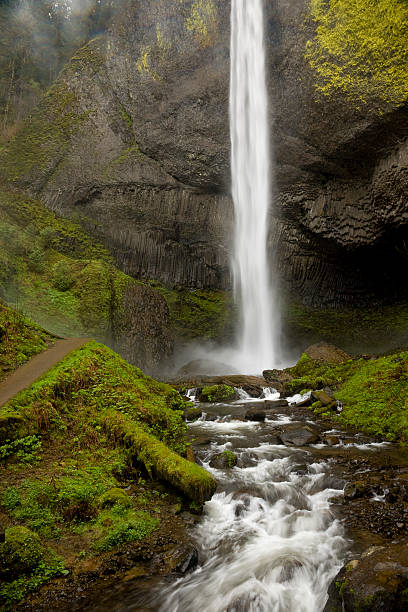 istock Water flowing over moss covered rocks with waterfall in background 182196608