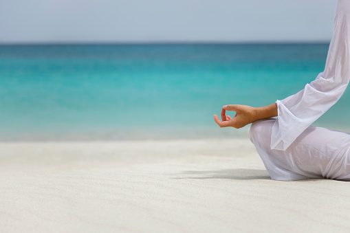 close-up on woman practicing yoga on tropical beach in the Caribbean